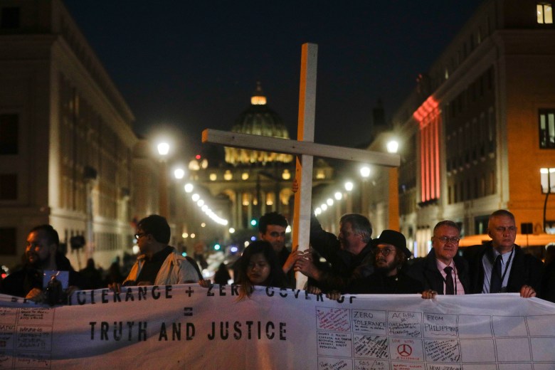 Survivors of sex abuse hold a cross as they gather in front of Via della Conciliazione, the road leading to St. Peter's Square, visible in background, during a twilight vigil prayer of the victims of sex abuse, in Rome, Thursday, Feb. 21, 2019 during a twilight vigil prayer near Castle Sant' Angelo, in Rome, Thursday, Feb. 21, 2019. Pope Francis opened a landmark sex abuse prevention summit Thursday by warning senior Catholic figures that the faithful are demanding concrete action against predator priests and not just words of condemnation. (AP Photo/Gregorio Borgia) Vatican Sex Abuse