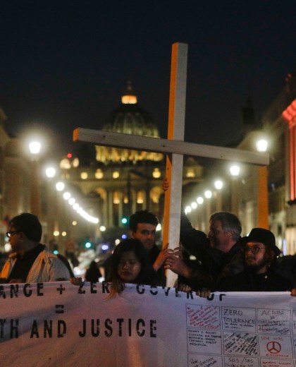 Survivors of sex abuse hold a cross as they gather in front of Via della Conciliazione, the road leading to St. Peter's Square, visible in background, during a twilight vigil prayer of the victims of sex abuse, in Rome, Thursday, Feb. 21, 2019 during a twilight vigil prayer near Castle Sant' Angelo, in Rome, Thursday, Feb. 21, 2019. Pope Francis opened a landmark sex abuse prevention summit Thursday by warning senior Catholic figures that the faithful are demanding concrete action against predator priests and not just words of condemnation. (AP Photo/Gregorio Borgia) Vatican Sex Abuse