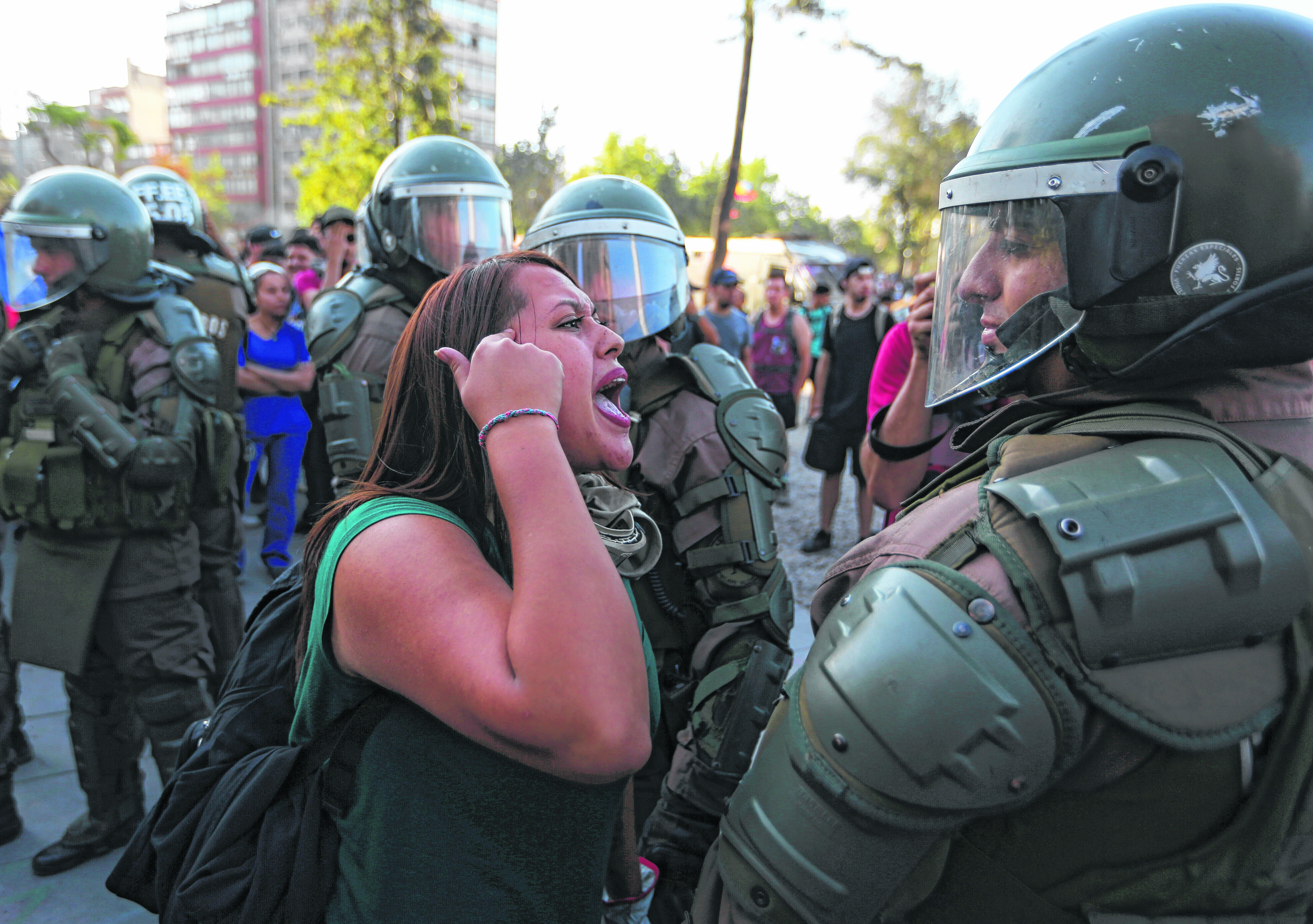 A demonstrator argues with an anti riot police officer during a protest in Santiago, Chile, Monday, Dec. 9, 2019. Student protests have become a nationwide call for socio-economic equality and better social services, so far forcing Chilean President Sebastian Pinera to increase benefits for the poor and disadvantaged and start a process of constitutional reform. (AP Photo/Fernando Llano)