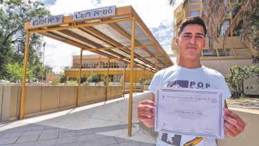 Miguel Angel Gutierrez, con diploma en mano en la fachada de su colegio, la ESRN N° 9.
