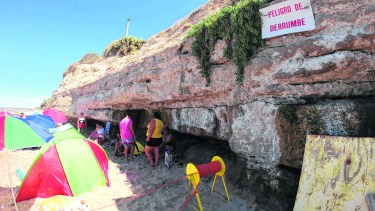 Los bañistas, con equipos, niños pequeños y hasta mascotas se guarecen bajo las bellas grutas que han hecho famoso el balneario. (Foto: Martin Brunella)