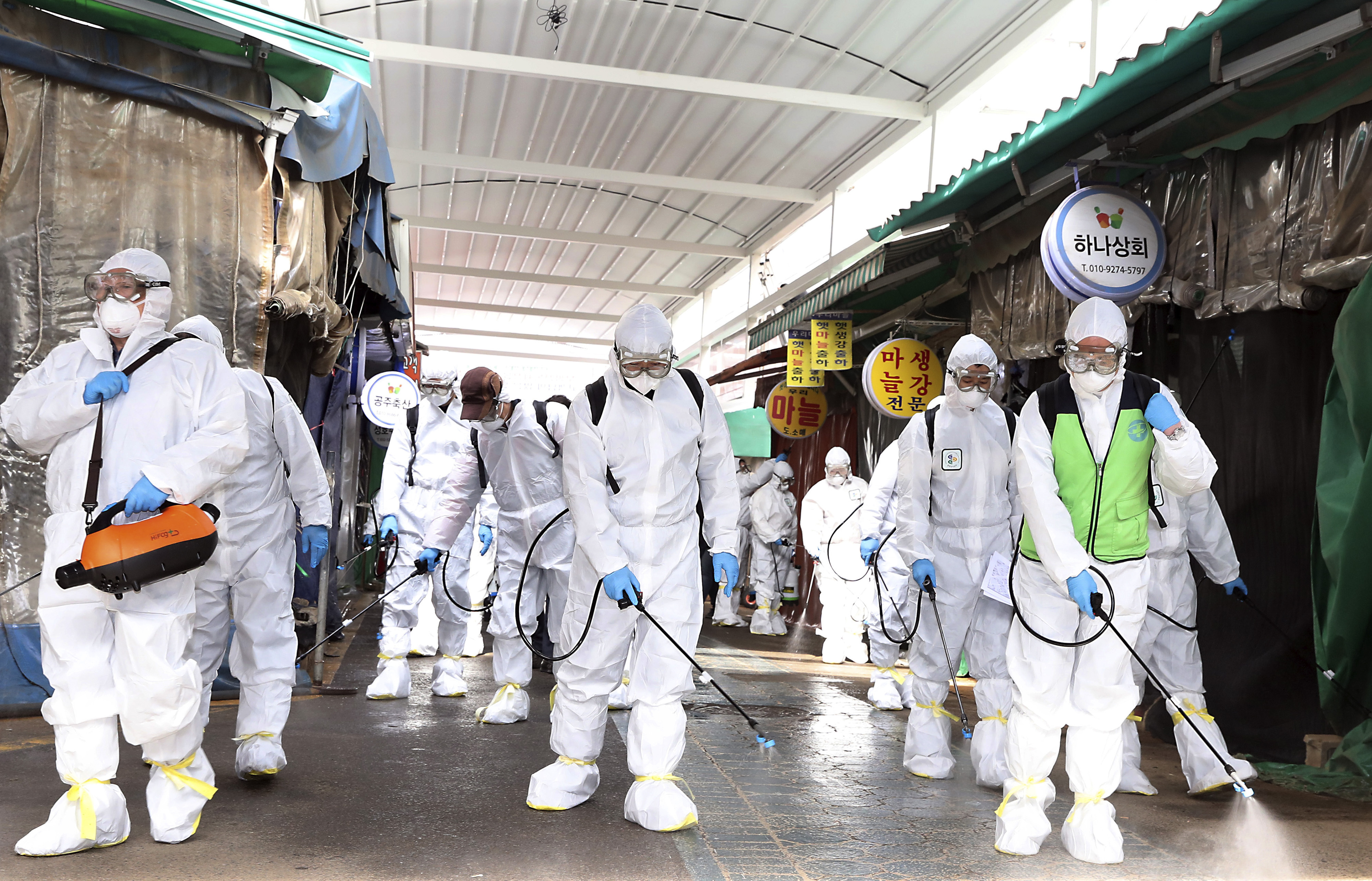 En Corea, trabajadores usan protección para desinfectar la zona de un mercado, de manera preventiva. Foto AP. 