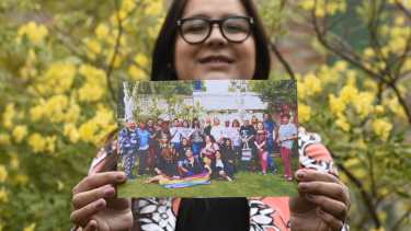 Tatiana sostiene una foto en la que aparecen todas sus compañeras. Dice que es una de sus favoritas porque están “todas sonriendo.” Foto Florencia Salto.