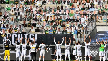 Una imagen por demás surrealista. Los jugadores del Borussia Moenchengladbach saludan a los “espectadores en modo cartulina” en las tribunas. (Foto/AP)