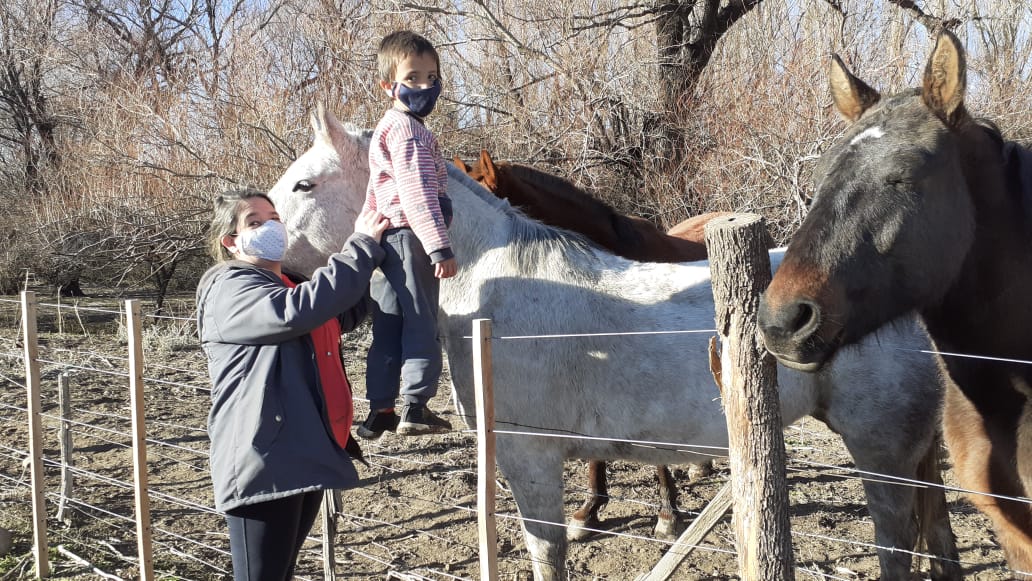 Iván y su mamá Vanesa junto a los caballos. El kinesiólogo recomendó equinoterapia. Y así pudo caminar. 