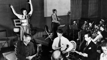 Orson Welles, con los brazos en alto, en plena emisión de "La Guerra de los Mundos" en los estudios de la CBS.