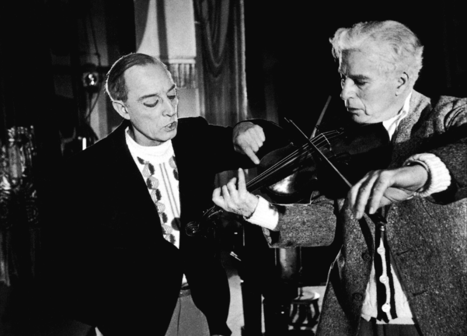 Chaplin toca el violín, ante la atenta mirada de Buster Keaton.