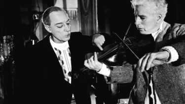 Chaplin toca el violín, ante la atenta mirada de Buster Keaton.