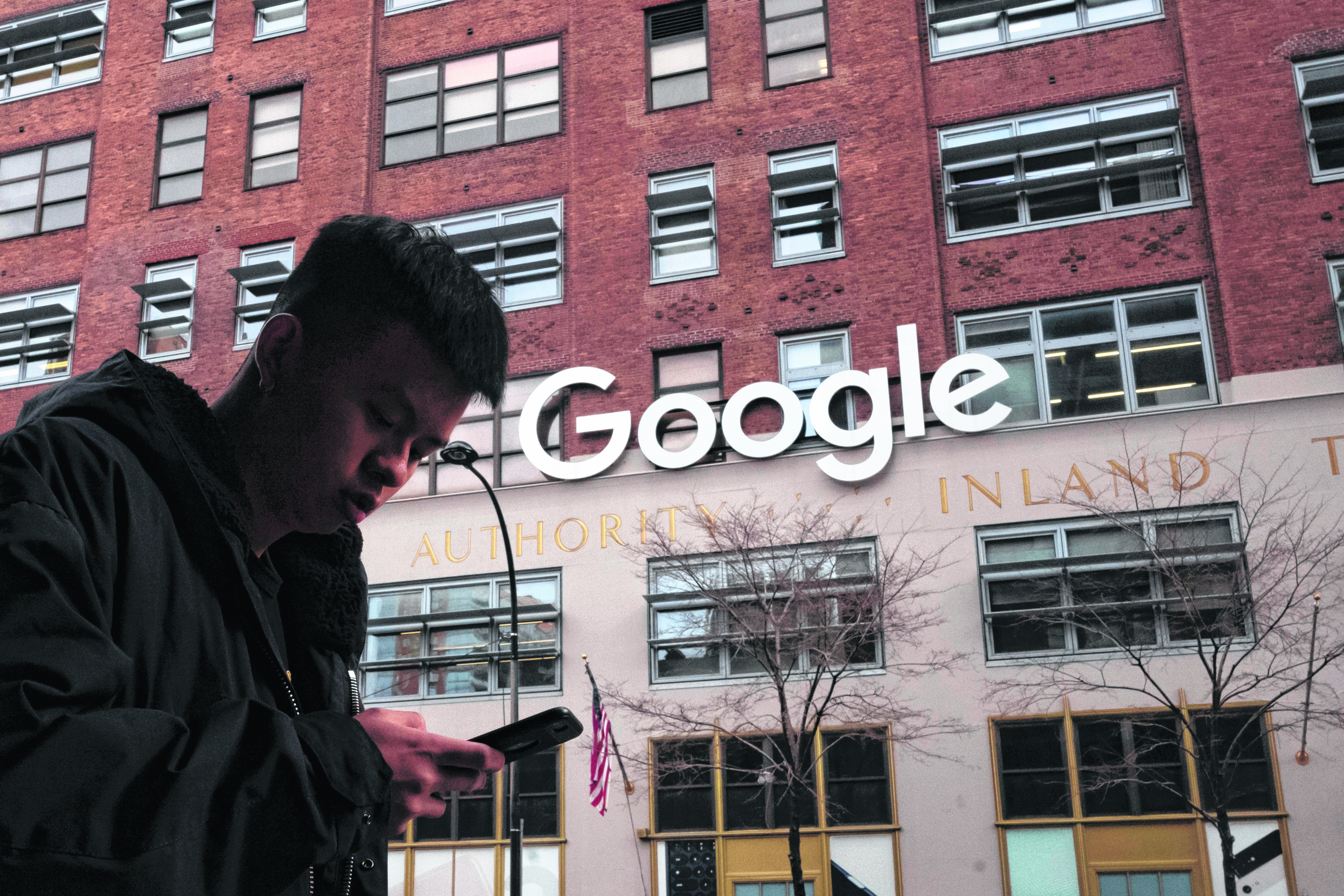 FILE - In this Dec. 17, 2018, file photo a man using a mobile phone walks past Google offices in New York. Australia’s laws forcing Google and Facebook to pay for news are ready to take effect, though the laws' architect said it will take time for the digital giants to strike media deals. The Parliament on Thursday, Feb . 25, 2021, passed amendments to the so-called News Media Bargaining Code agreed between Treasurer Josh Frydenberg and Facebook chief executive Mark Zuckerberg on Tuesday. (AP Photo/Mark Lennihan, File)