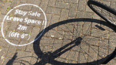 FILE - In this file photo dated May 7, 2020, a social distancing message during the coronavirus outbreak on a street during a bike ride in London, May 7, 2020.  Pedal bike thefts have jumped by two thirds since the coronavirus lockdowns started, according to information released by home insurer Admiral, Wednesday March 31, 2021. (AP Photo/Nino Bantic, FILE)