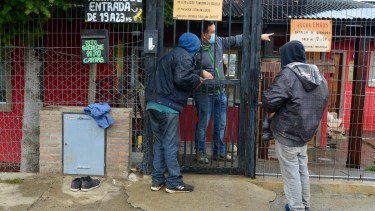 En la puerta del hogar Emaús, dos hombres en situación de calle se acercan para recibir un plato de comida y ropa seca. Foto: Chino Leiva