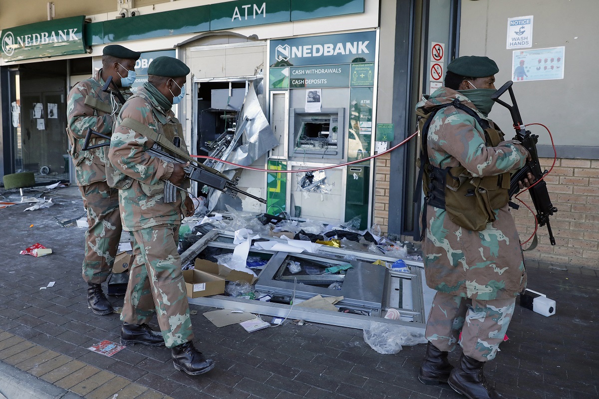 Miembros de la Fuerza de Defensa Sudafricana (SANDF) pasan junto a un cajero automático mientras patrullan el área saqueada de Diepkloof Square en Soweto, Johannesburgo (Foto de Phill Magakoe / AFP)