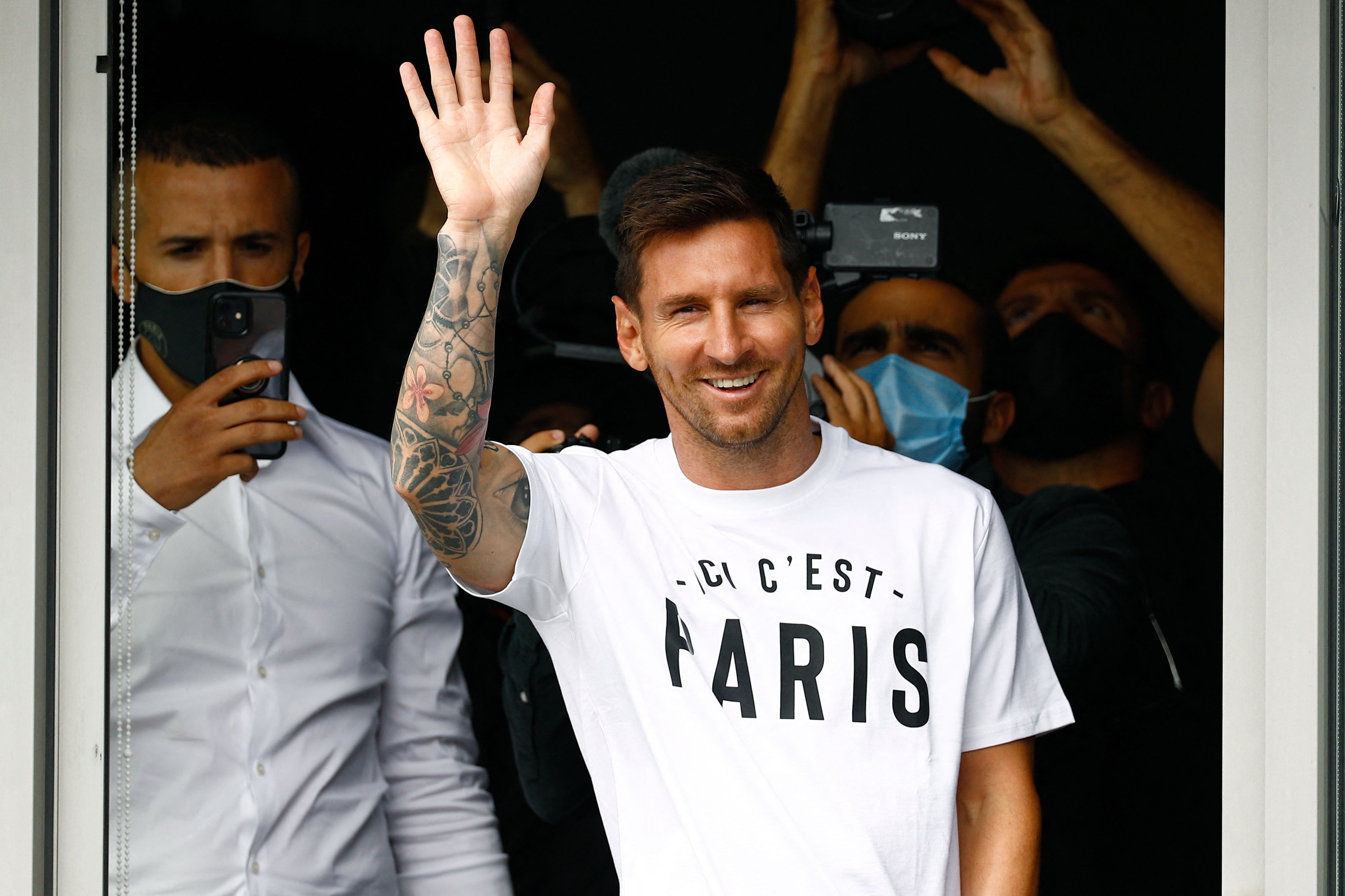 El futbolista argentino Lionel Messi saluda a los aficionados desde una ventana después de aterrizar en el aeropuerto de Le Bourget. Foto: Télam
