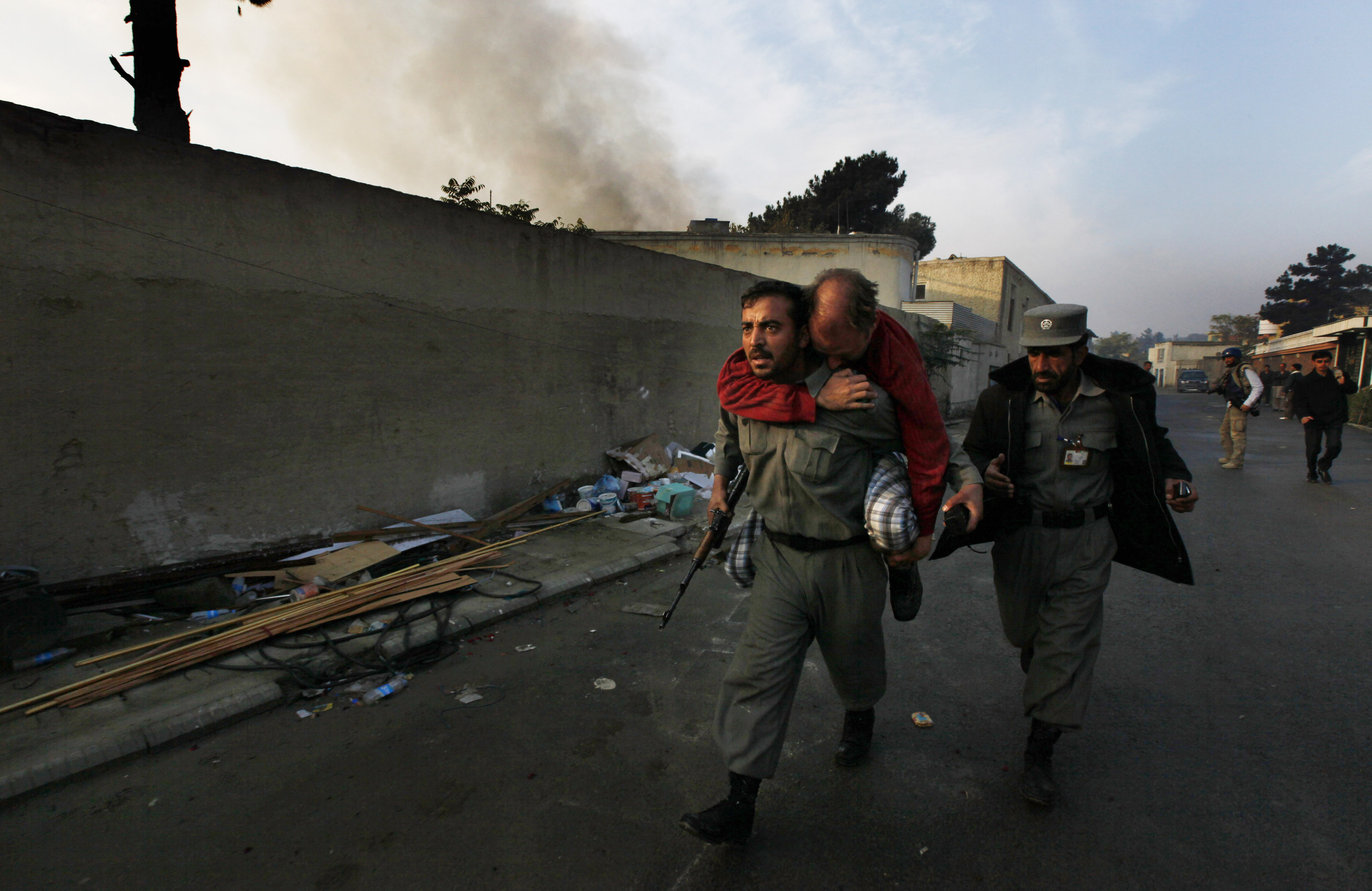 Un policía afgano transporta a un  herido durante uan escaramuza en Kabul  