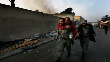 Un policía afgano transporta a un  herido durante uan escaramuza en Kabul  