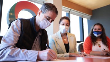 Roccatagliata firma la escritura ante la mirada de la gobernadora Carreras.