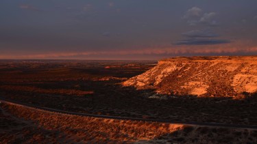 Atardecer en la ruta 6, con las bardas en primer plano y las chacras y Roca de fondo. Foto: Alejandro Carnevale.
