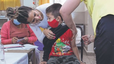 "Sí que duele má". Toda la contención posible se desplegó en las salitas de vacunación en las escuelas de Roca.  Foto Juan Thomes