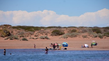 El agua tiene un tinte azul y es cálida, por la escasa profundidad, la tierra naranja y el verde de los arbustos componen el paisaje. Fotos Emiliana Cantera.