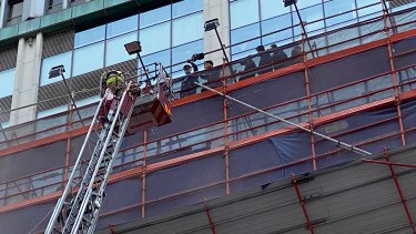 People rescued by a firefighter at the World Trade Centre where is located in the city's popular Causeway Bay shopping district of Hong Kong, Wednesday, Dec. 15, 2021. Dozens of people are trapped on the rooftop of the Hong Kong skyscraper after a major fire broke out Wednesday, as firefighters rushed to rescue them and put out the blaze. (AP Photo)