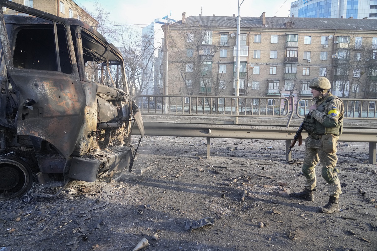 Un soldado ucraniano pasa junto a los restos de un camión militar en llamas en una calle de Kiev. Foto: AP 
