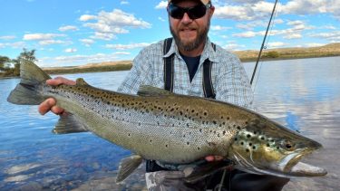 César "Ruso" Castellano y la gran trucha marrón migratoria que pescó el sábado pasado en el Limay Medio, cerca de la desembocadura, al norte de la Patagonia. 