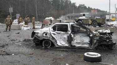 Militares ucranianos se paran cerca de un automóvil dañado y un vehículo blindado en un puesto de control en Brovary, en las afueras de Kiev, Ucrania. (Foto AP/Efrem Lukatsky)