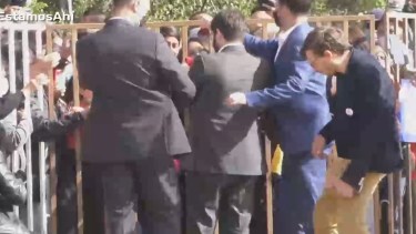 El momento en que la piedra impacta en uno de los funcionarios de Boric. 