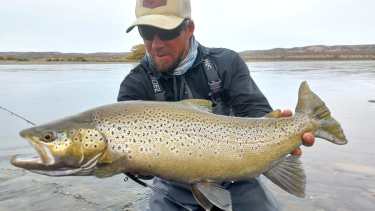 El guía Pablo Oscar Blasco y una de las grandes truchas marrones migratorias del Limay Medio, el río que corre entre Neuquén y Río Negro al norte de la Patagonia. 