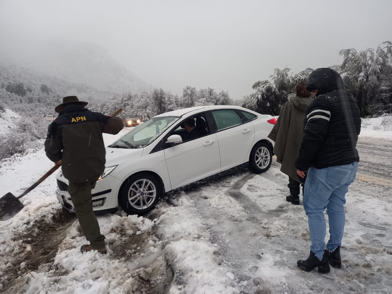 Personal de Parques Nacionales auxilia a un conductor, cuyo vehículo quedó atascado en la nieve por el temporal. (foto gentileza)