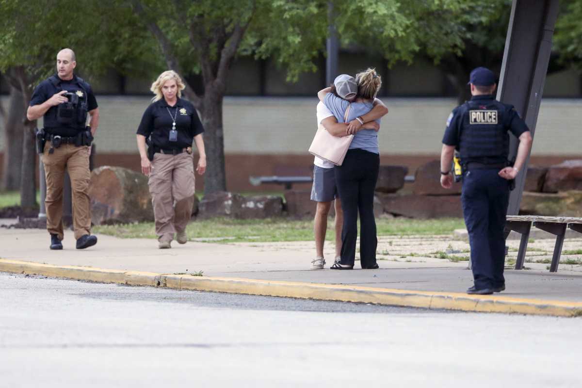 Dos personas se abrazan afuera de Memorial High School, donde las personas fueron evacuadas de la escena de un tiroteo en el edificio médico Natalie el miércoles  (Ian Maule/Tulsa World via AP)