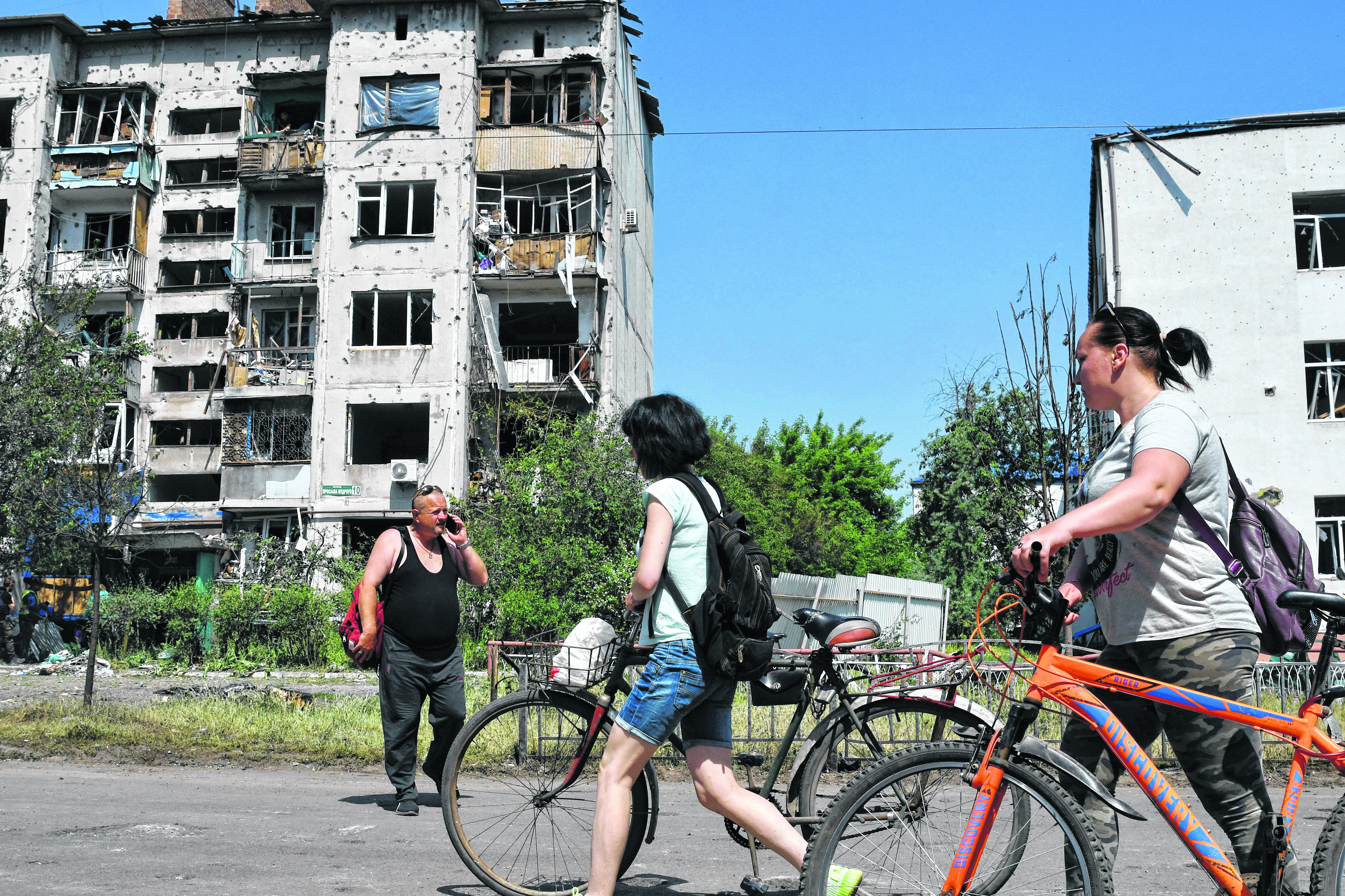 People walk past a building damaged by an overnight missile strike, in Sloviansk, Ukraine, Tuesday, May 31, 2022. (AP Photo/Andriy Andriyenko)