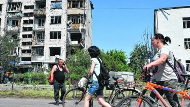 People walk past a building damaged by an overnight missile strike, in Sloviansk, Ukraine, Tuesday, May 31, 2022. (AP Photo/Andriy Andriyenko)