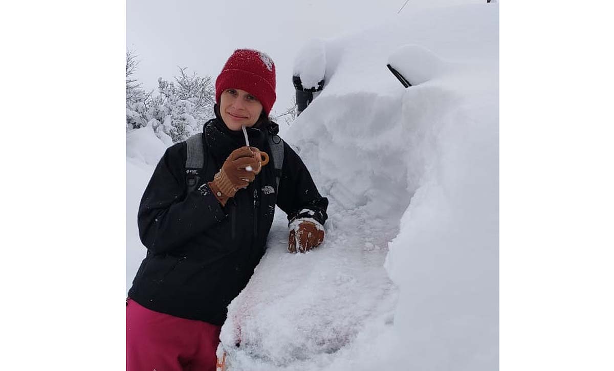 La camioneta tapada por la nieve. Ariadna y un matecito antes de ponerse a palear con Nico para poder salir al camino en este paraíso neuquino de la Patagonia. Foto: Nico Pollo.