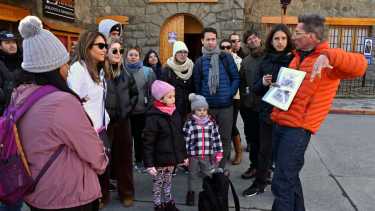 Con paraguas naranja abierto para ser reconocido por el grupo, Máximo Daulte, sale cada día a las 9:45 a guiar el tour “Descubre la historia de Bariloche”. Fpto: Alfredo Leiva.