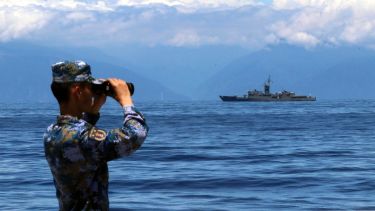 In this photo provided by China’s Xinhua News Agency, a People's Liberation Army member looks through binoculars during military exercises as Taiwan’s frigate Lan Yang is seen at the rear, on Friday, Aug. 5, 2022. China is holding drills in waters around Taiwan in response to a recent visit by U.S. House Speaker Nancy Pelosi. (Lin Jian/Xinhua via AP)