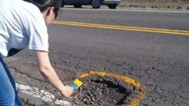 Beatriz y su hija salieron a pintar los baches de la ruta para que, al menos, queden señalizados. (Gentileza).-