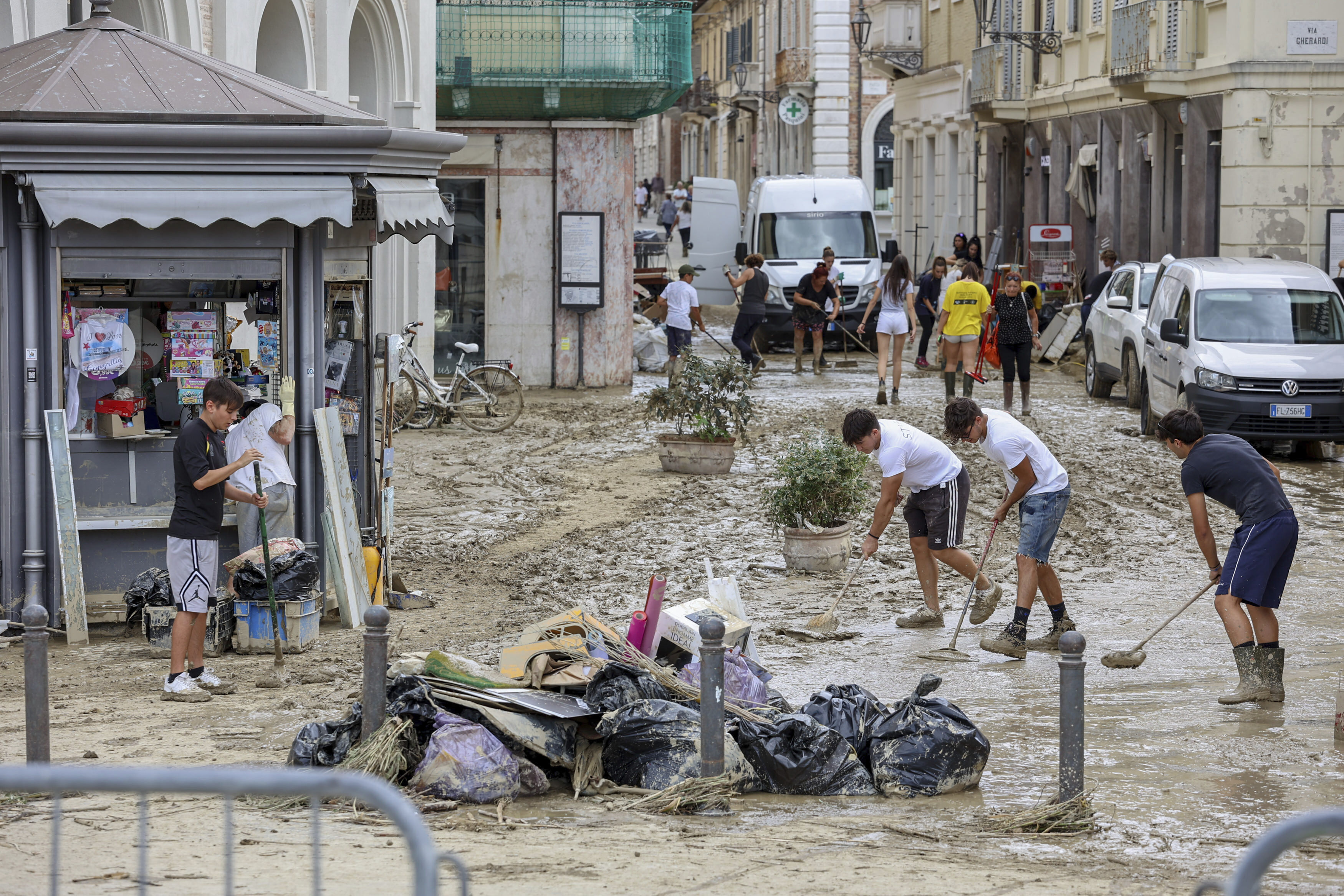 People remove mud from a street in Senigallia, central Italy, Friday Sept. 16, 2022. Flash floods triggered by heavy rain have swept through towns in a hilly central Italy.  Italy's leader Mario Draghi said 10 people were dead in the floods and four were missing. (Guido Calamosca/LaPresse via AP)