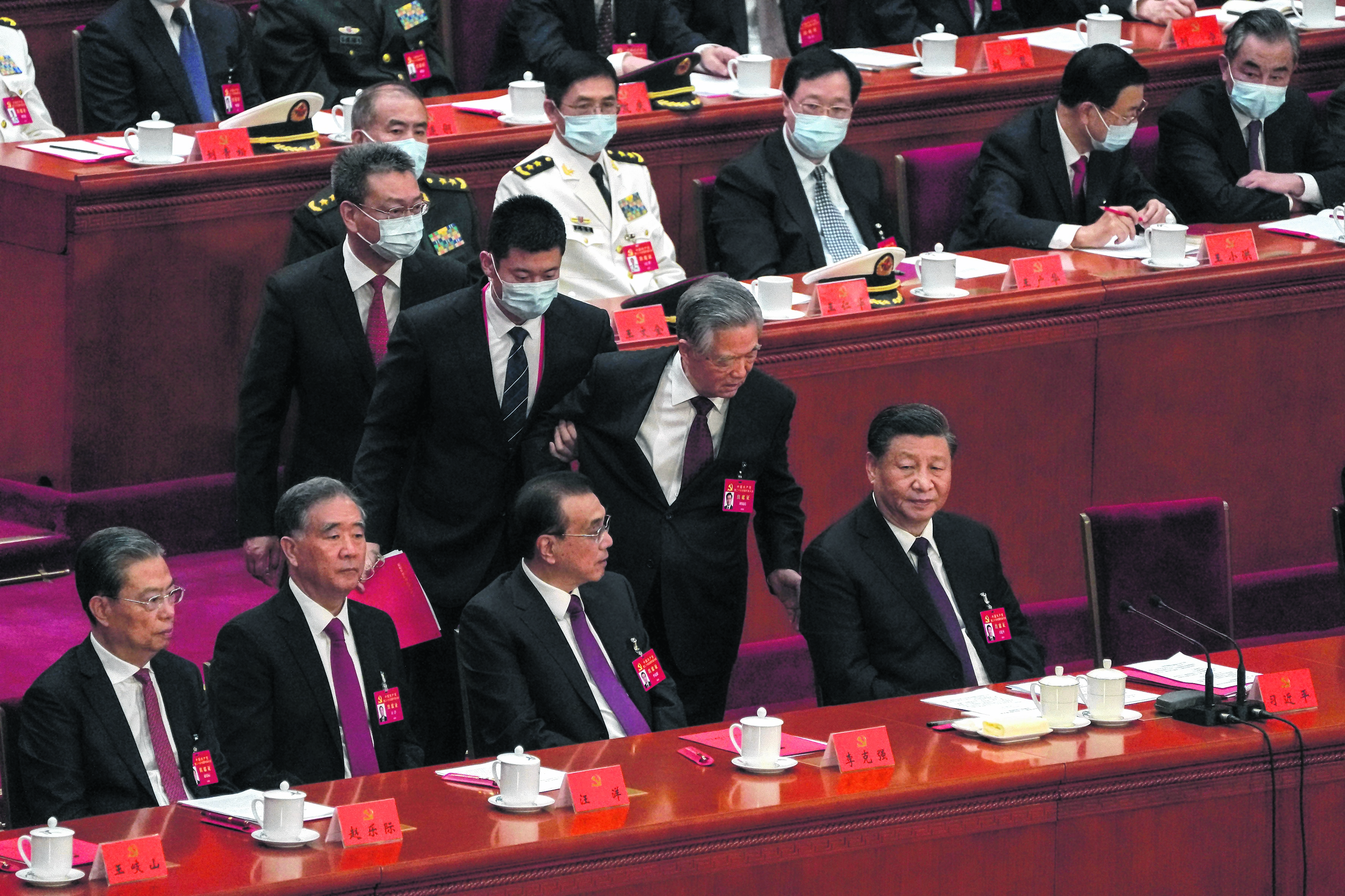 Hu Jintao intenta decirle algo al presidente, antes de que se lo lleven.
