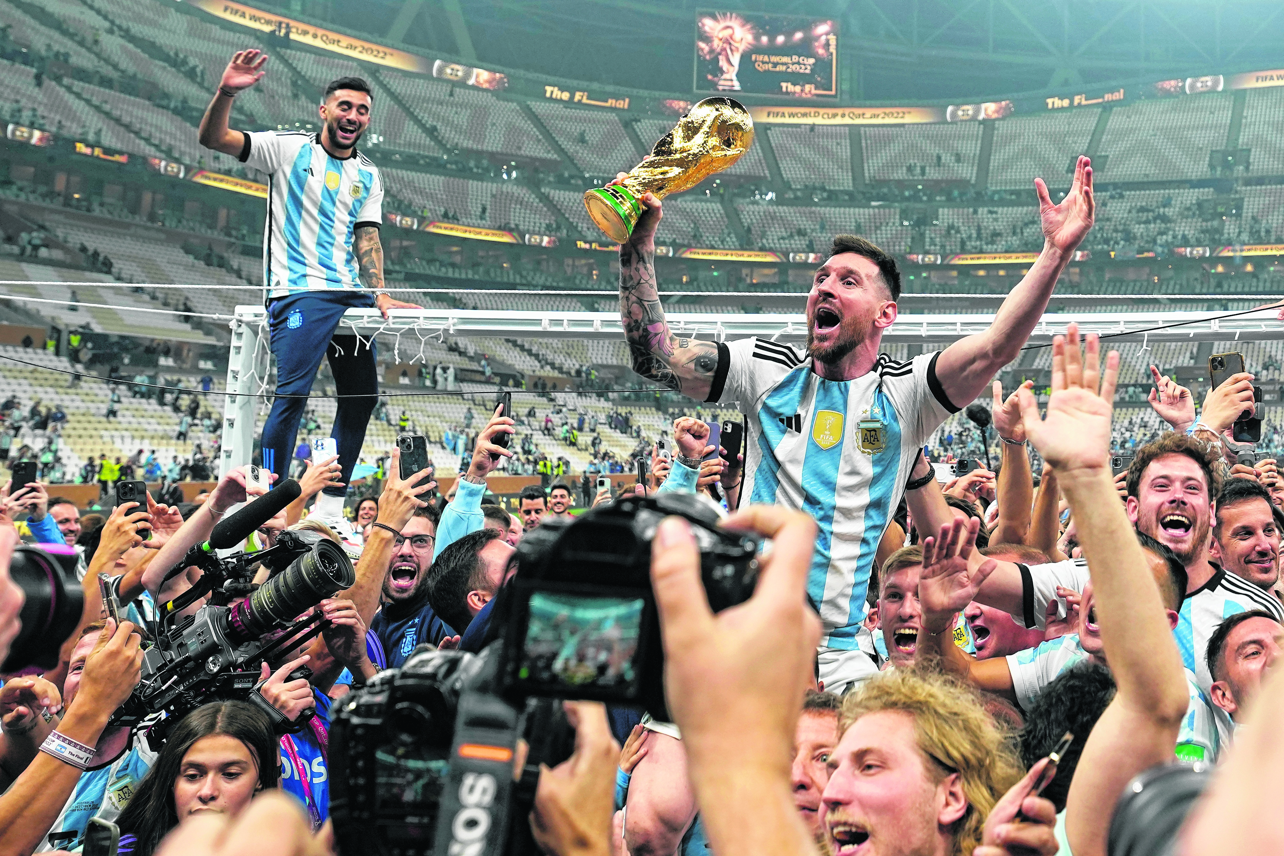 Lionel Messi celebra con el trofeo de campeón mundial con los hinchas de Argentina tras la victoria ante Francia por penales en la final del Mundial. (AP Foto/Martin Meissner)