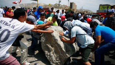 Supporters of ousted Peruvian President Pedro Castillo work together to roll a boulder onto the Pan-American North Highway during a protest against his detention, in Chao, Peru, Thursday, Dec. 15, 2022. Peru's new government declared a 30-day national emergency on Wednesday amid violent protests following Castillo's ouster, suspending the rights of "personal security and freedom" across the Andean nation. (AP Photo/Hugo Curotto)
