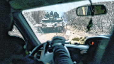 A Ukrainian tank with soldiers is seen through a car window close to the frontline near Kremenna in the Luhansk region, Ukraine, Sunday, Jan. 15, 2023. (AP Photo/LIBKOS)
