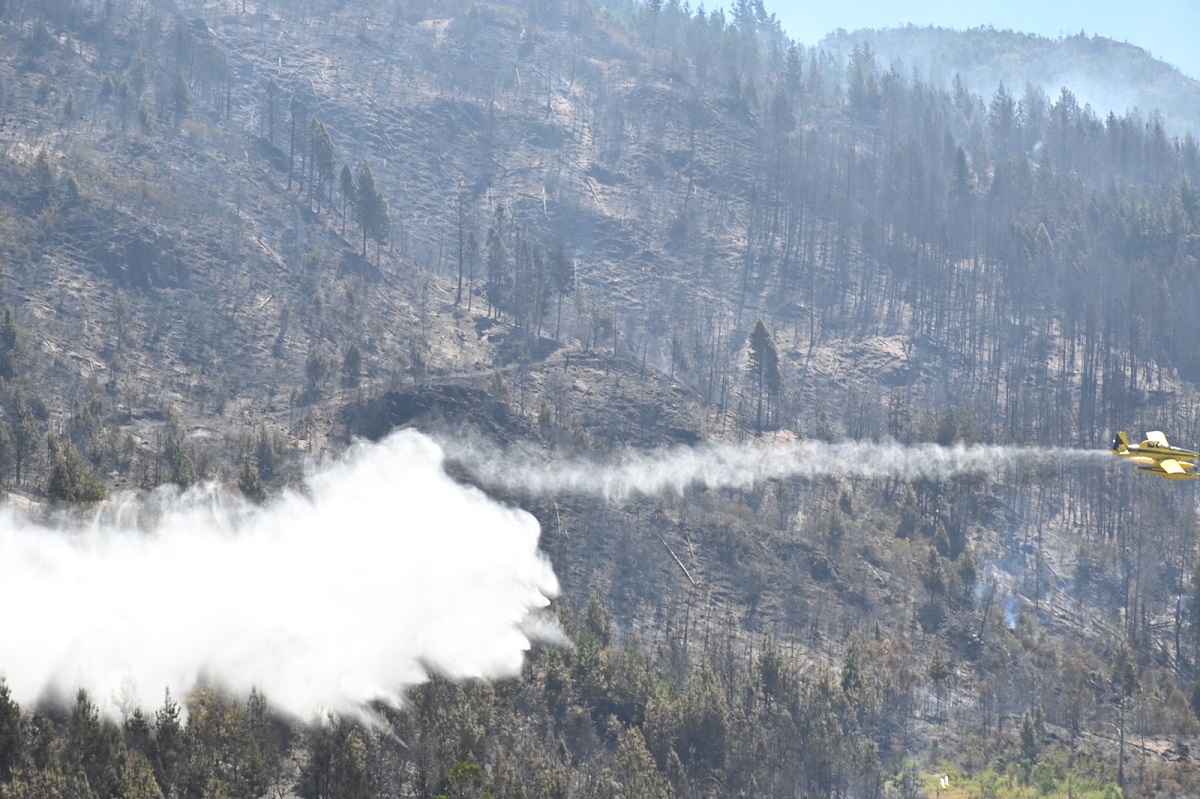 Un avión hidrante sobrevuela la zona quemada arrojando agua en el cerro Currumahuida. Foto: Chino Leiva