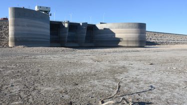 El vertedero del dique Casa de Piedra quedó desconectado del lago que se retiró. La cota es la segunda más baja desde el llenado. Foto Juan Thomes.
