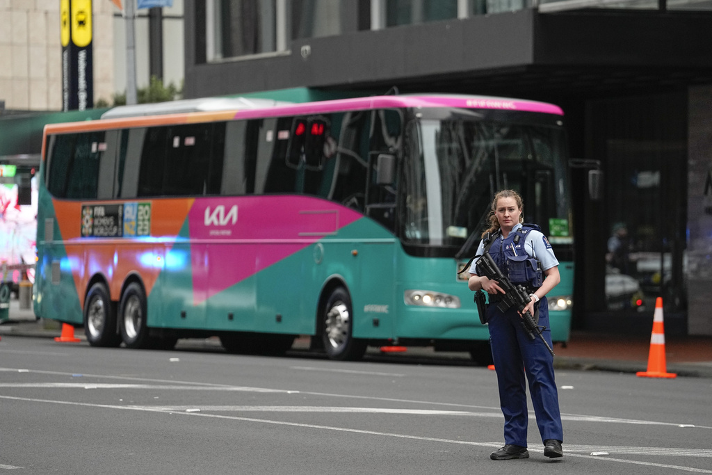 Una policía armada custodia uno de los colectivos que llevará a los planteles al estadio luego del tiroteo en Auckland. (AP Photo/Abbie Parr)