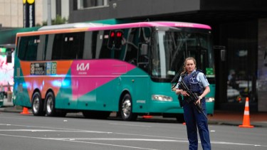 Una policía armada custodia uno de los colectivos que llevará a los planteles al estadio luego del tiroteo en Auckland. (AP Photo/Abbie Parr)