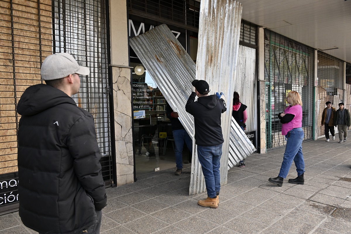 Esta tarde, comerciantes colocaban chapas en las vidrieras de sus locales en la calle Onelli de Bariloche. Foto: Chino Leiva