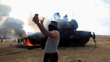 Un palestino se saca una selfie frente a un tanque israelí en llamas cerca de la frontera con la Franja de Gaza Foto: Yasser Qudih