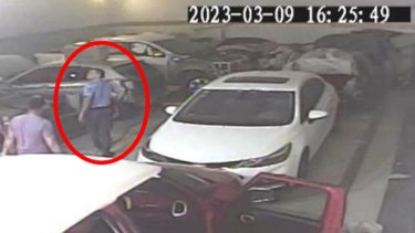 El policía López, mano en el arma, camina por el taller segundos antes de disparar. Detrás de él se ve a Lucas, al fondo está quien sería la víctima. (Captura de video)