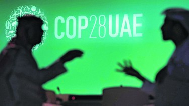 FILE - People are silhouetted against a logo for the COP28 U.N. Climate Summit, Nov. 29, 2023, in Dubai, United Arab Emirates. (AP Photo/Rafiq Maqbool, File)